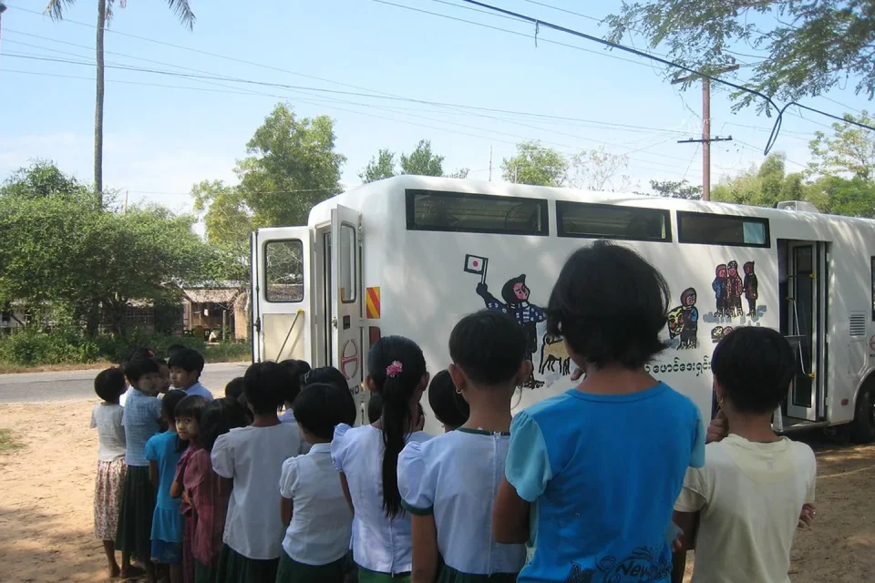 Bibliobús abierto atiende a lectores en una pequeña plaza rural.