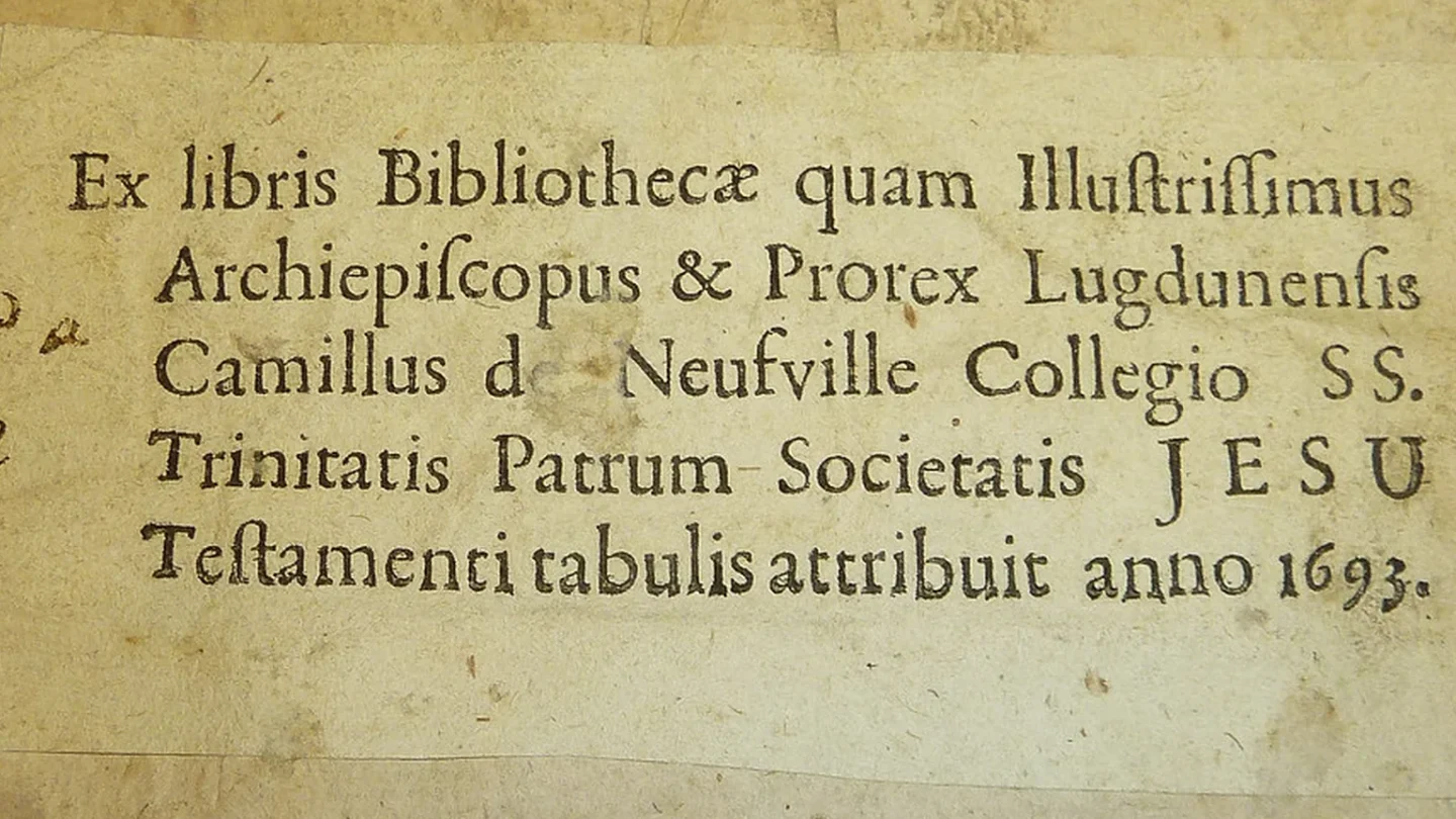 Libro antiguo abierto con una pequeña estampa ex libris pegada en la guarda