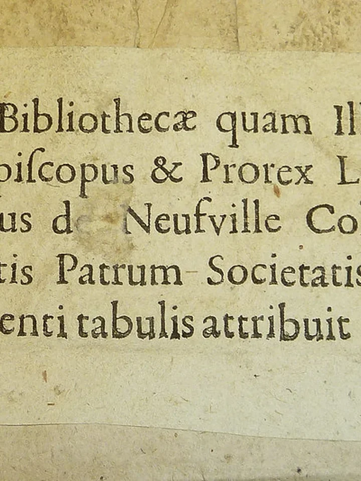 Libro antiguo abierto con una pequeña estampa ex libris pegada en la guarda
