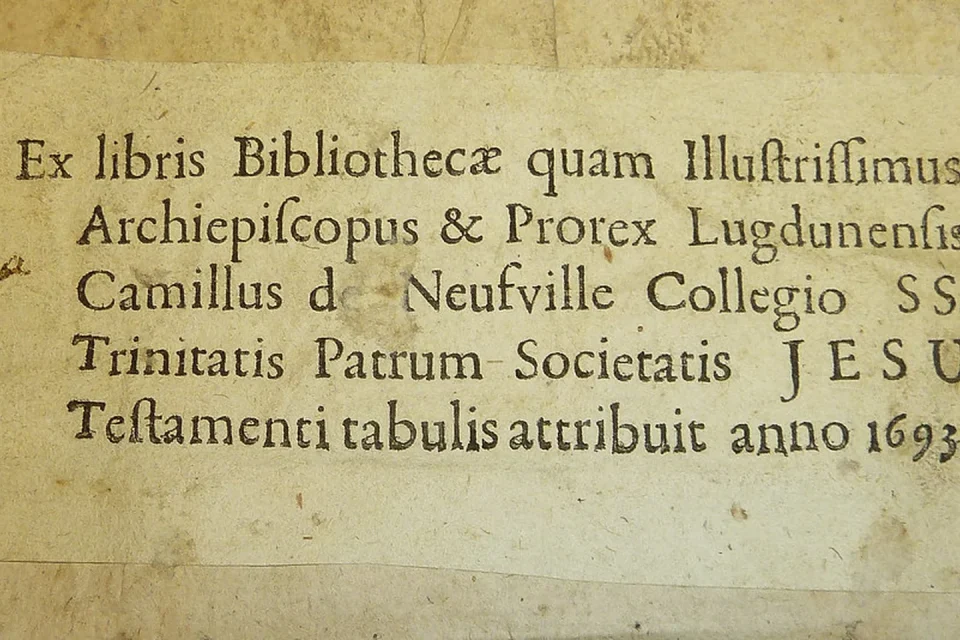 Libro antiguo abierto con una pequeña estampa ex libris pegada en la guarda