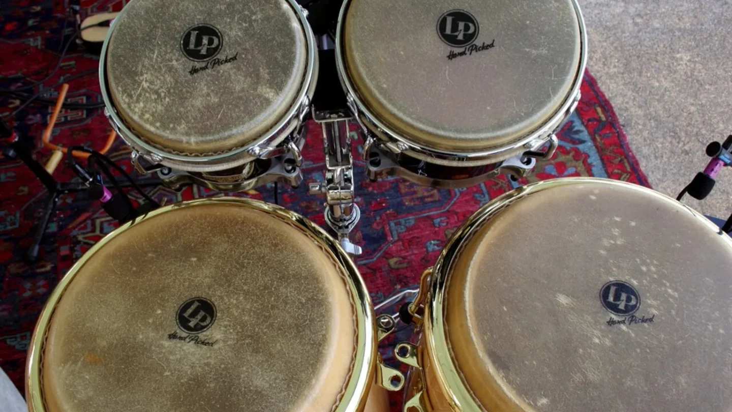 Instrumentos acústicos y electrónicos reunidos alrededor de una mesa de mezcla